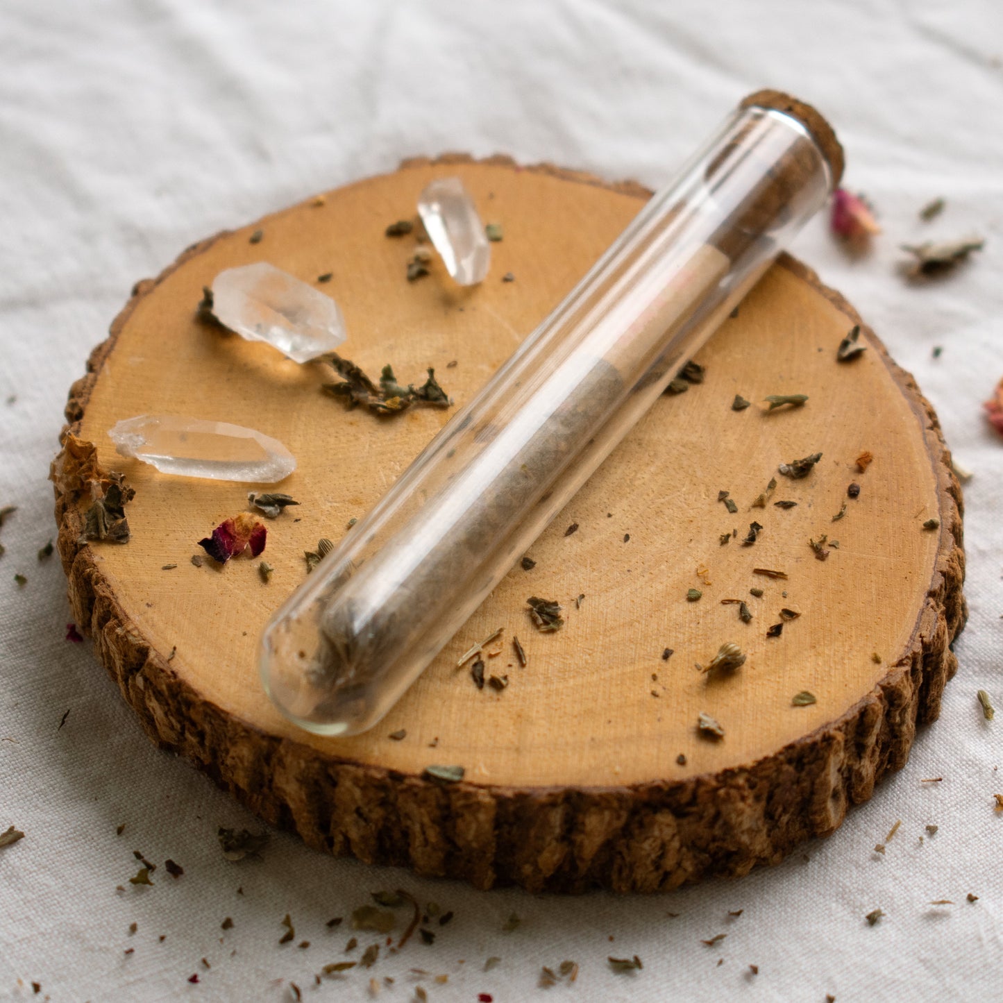 Organic Herbal Smoking Blend single pre roll in glass package on display surrounded by crystals and herbs for energetic balance and mindfulness