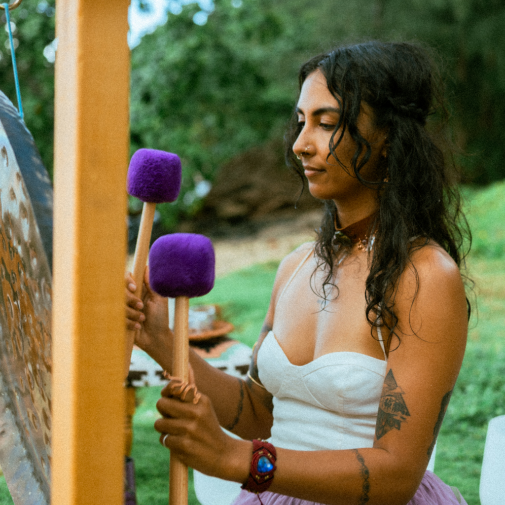 Woman playing a large gong outdoors with a natural background
