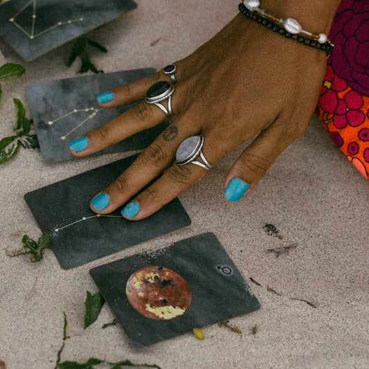 Astrology cards are displayed in the hand of an energy healer showcasing astrology reading services