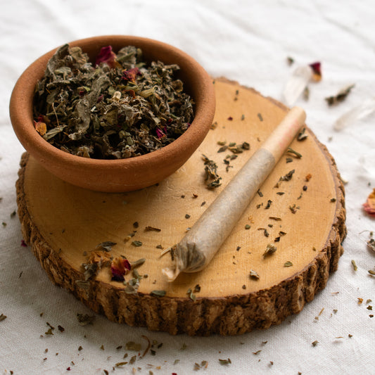 Organic Herbal Smoking Blend pre roll on display surrounded by herbs for energetic balance and mindfulness