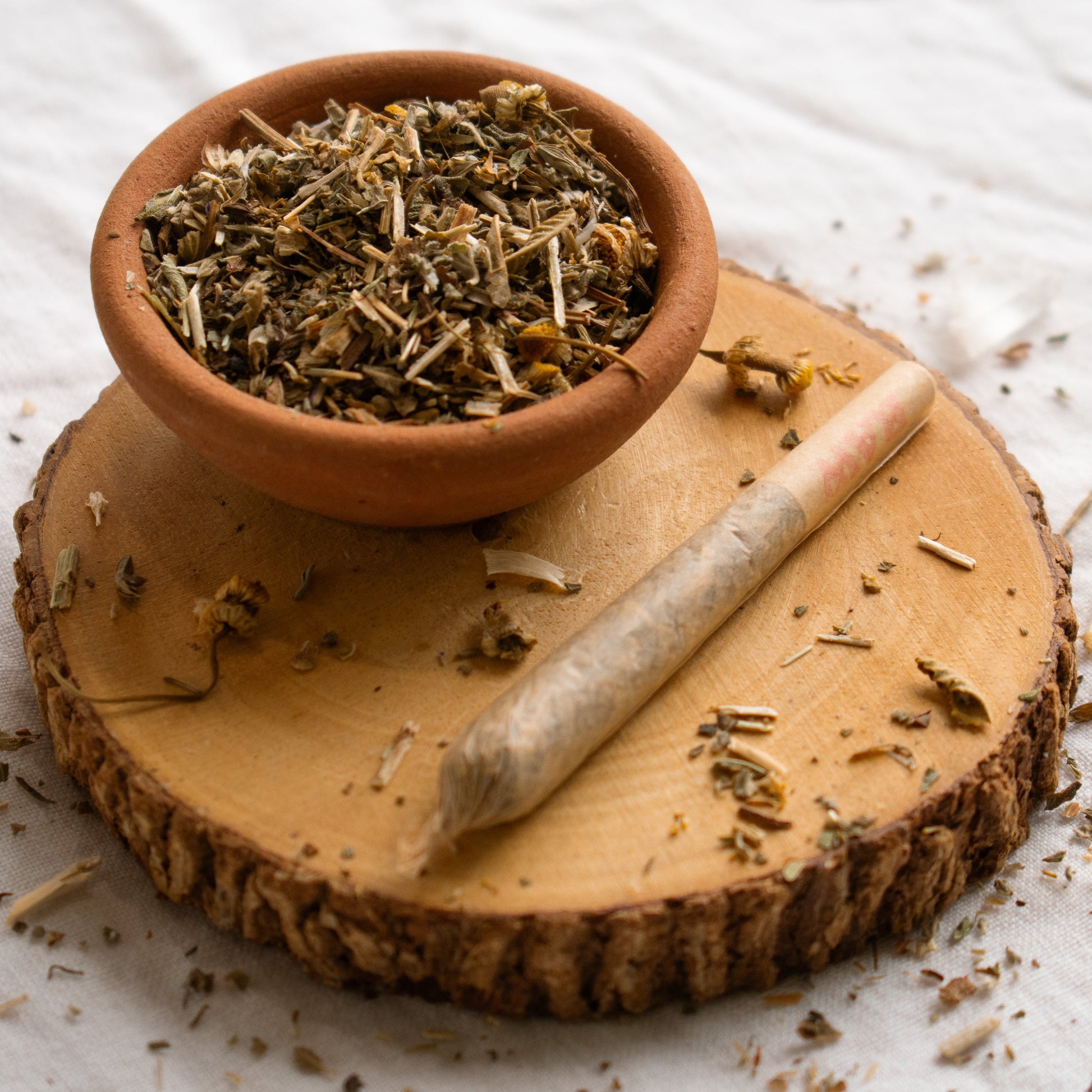 Organic Herbal Smoking Blend pre roll on display surrounded by herbs for energetic balance and 