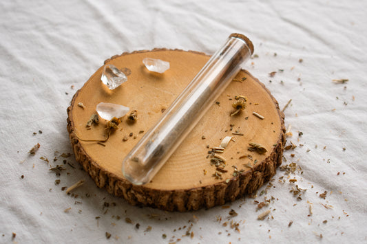 Organic Herbal Smoking Blend single pre roll in glass package on display surrounded by crystals and herbs for energetic balance and mindfulness