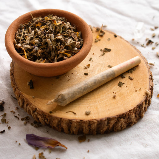 Organic Herbal Smoking Blend pre roll on display surrounded by herbs for energetic balance and mindfulness