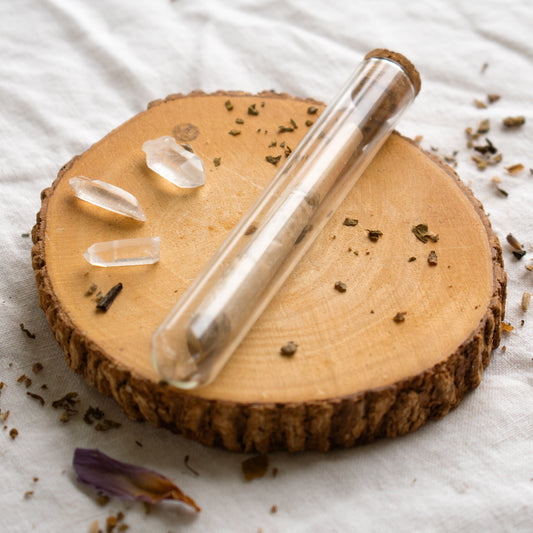 Organic Herbal Smoking Blend single pre roll in glass package on display surrounded by crystals and herbs for energetic balance and mindfulness