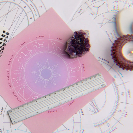 Natal charts displayed on a table next to crystals and candles for a natal chart reading service