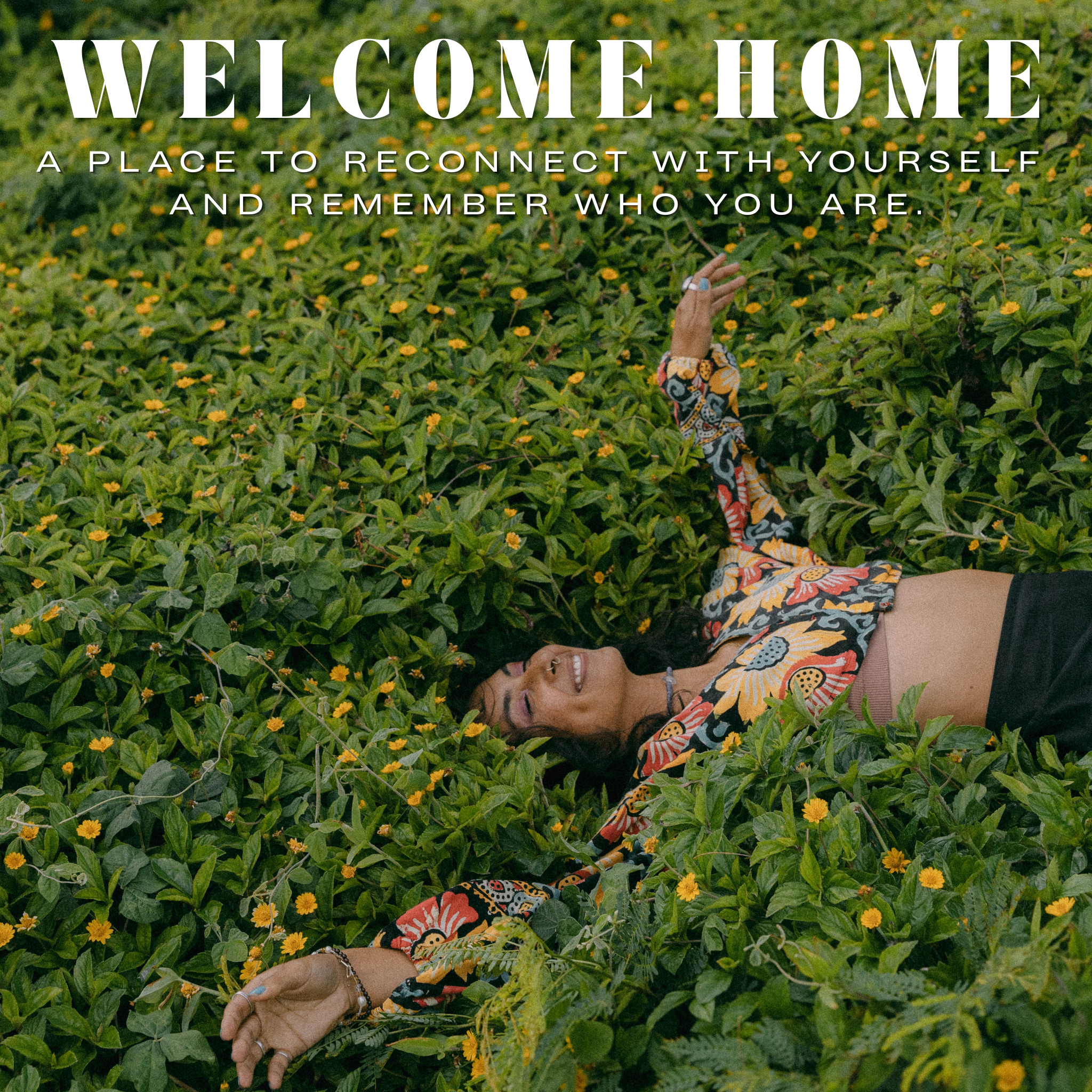 A woman lies face down in a dense patch of green plants with small yellow flowers, wearing a colorful patterned long-sleeve crop top and black shorts. Large white text at the top reads 'WELCOME HOME' with smaller text below.